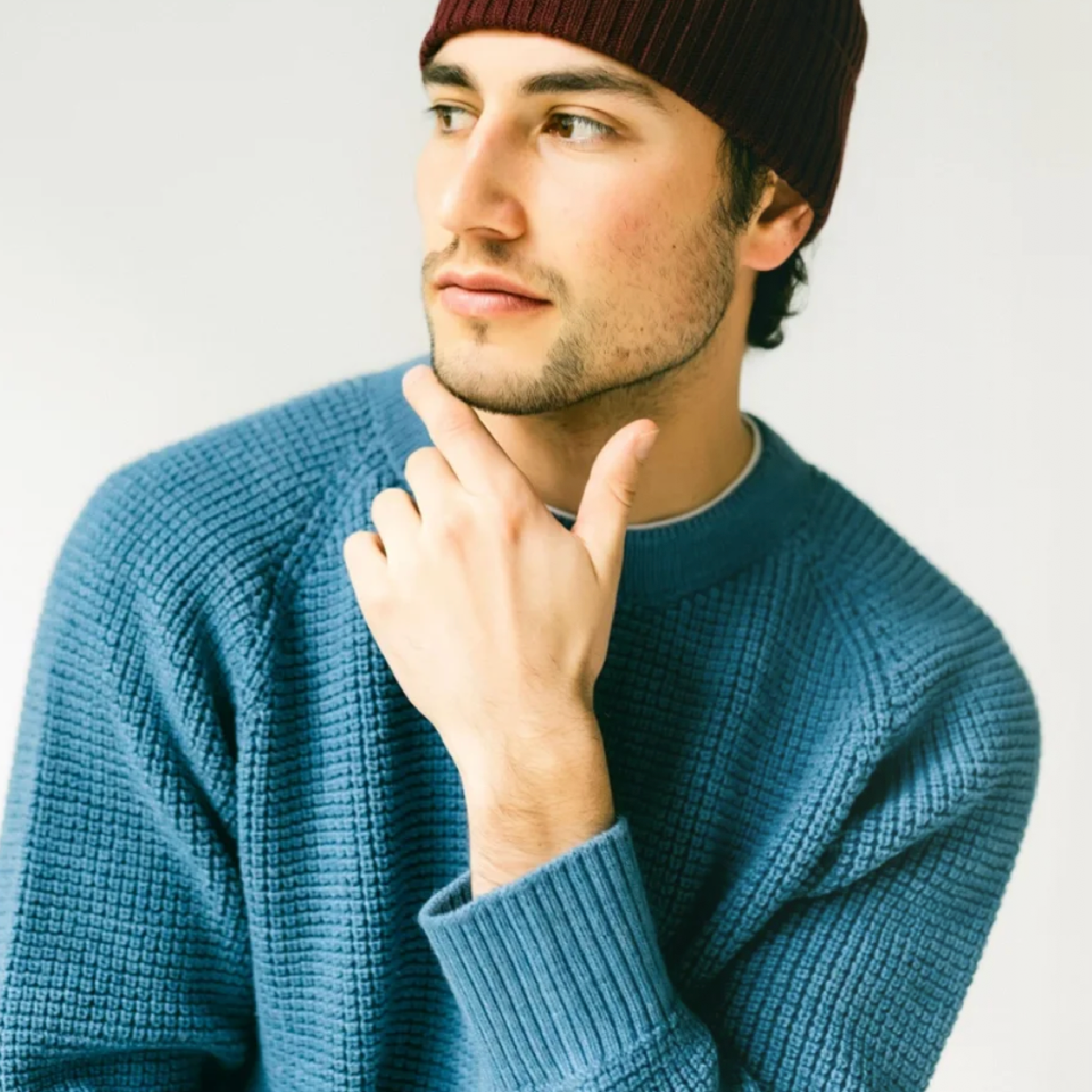 An aqua color sweater with a chunky waffle texture on worn by a man.