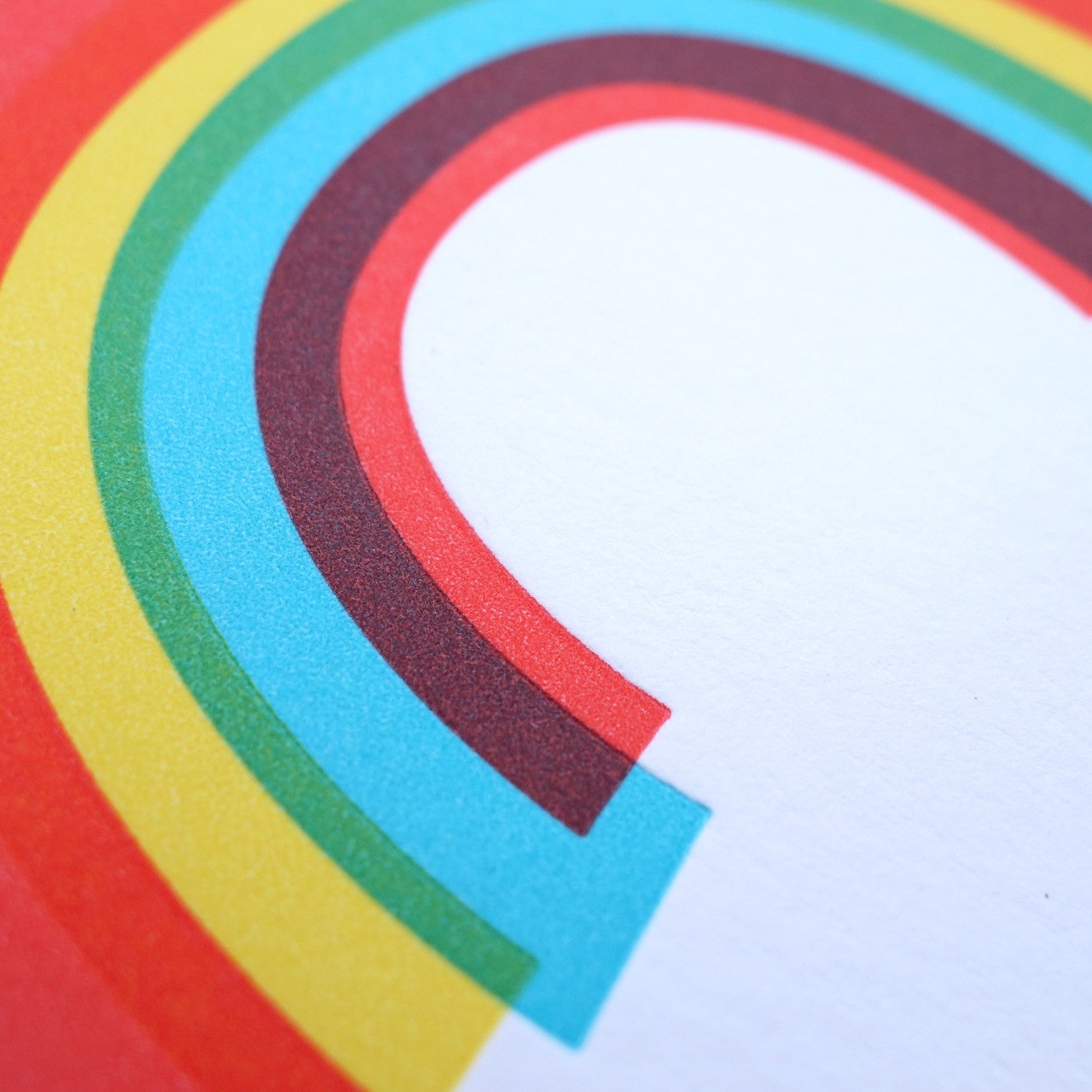 Detail of the letterpress texture of a white greeting card with a rainbow