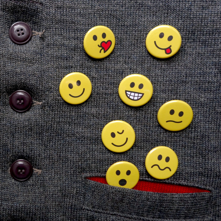 A collection of small pin buttons with different emotional faces