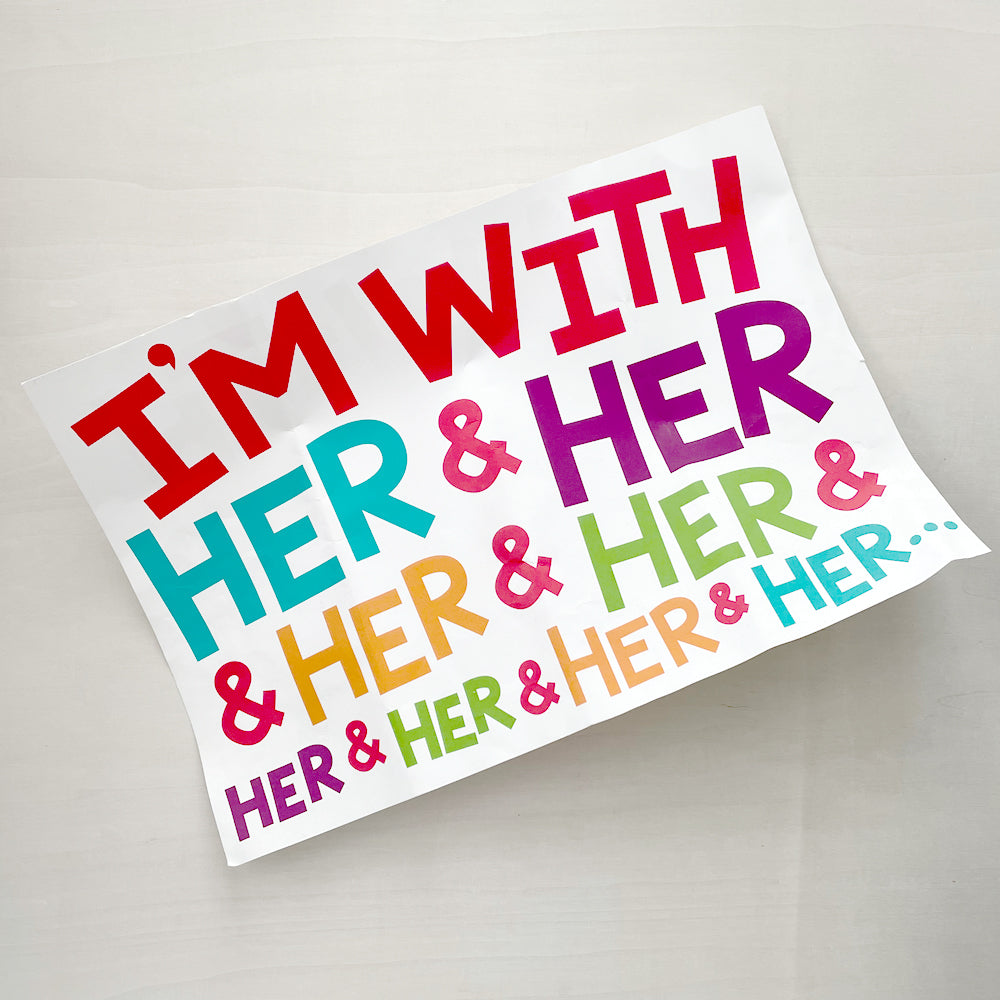 A printed sign reading "I'm With Her & Her & Her & Her & Her & Her & Her & Her & Her...